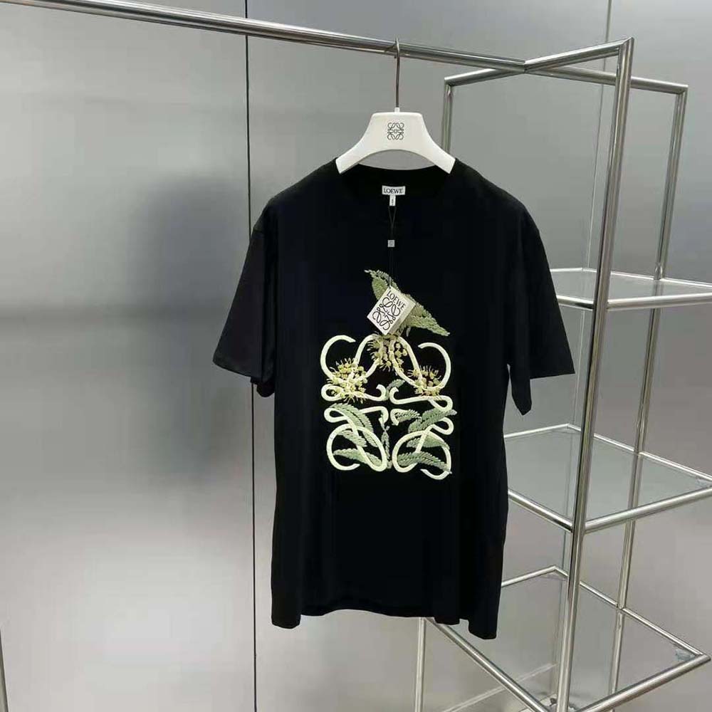 Close-up of embossed Herbarium Anagram logo detail on black T-shirt