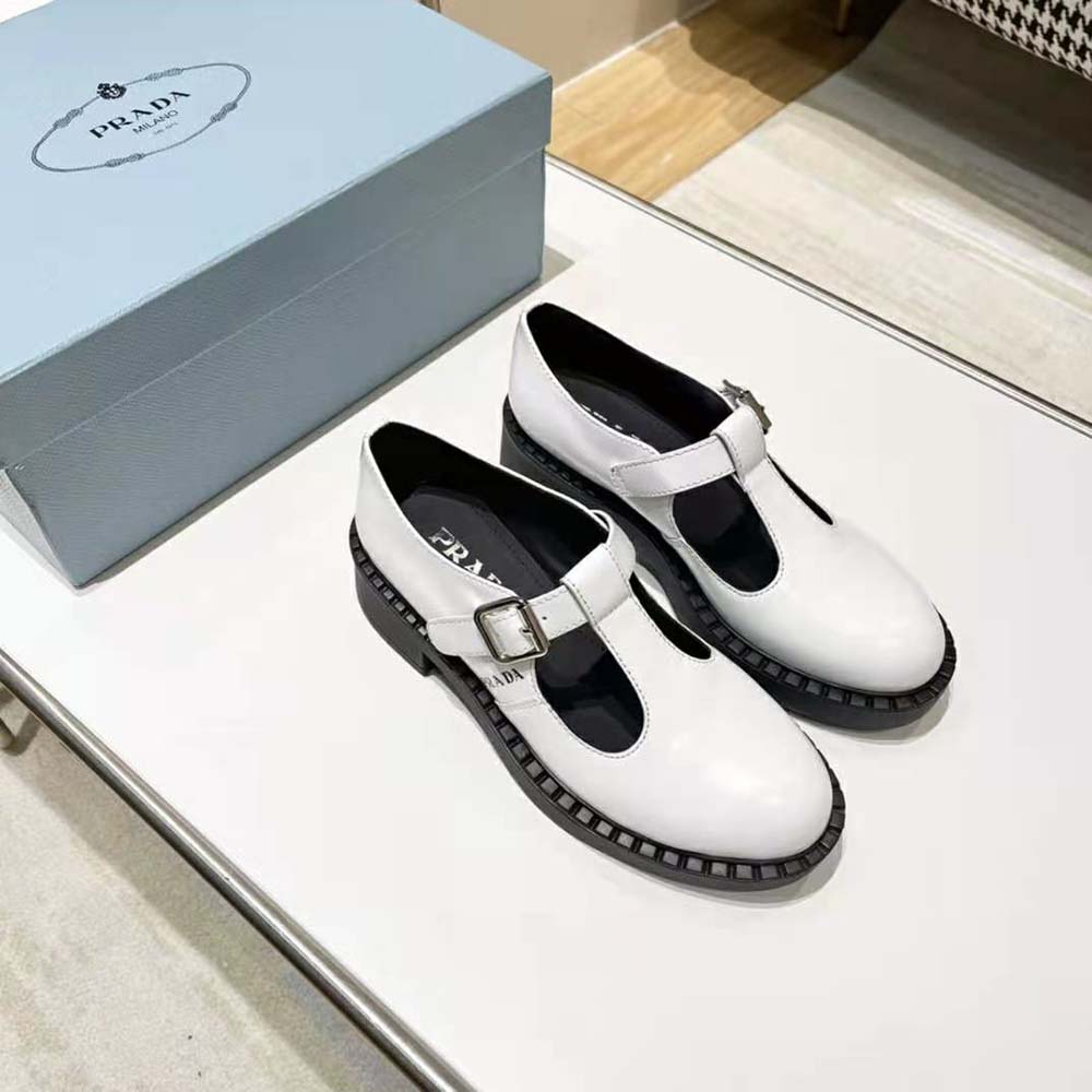 Top-down detail of T-strap and silver buckle on Prada white Mary Janes