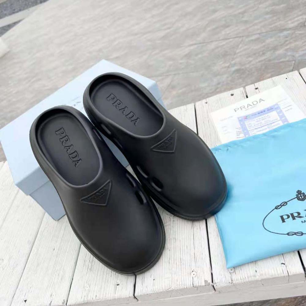 Close-up detail of embossed rubber triangle logo on Prada black mules