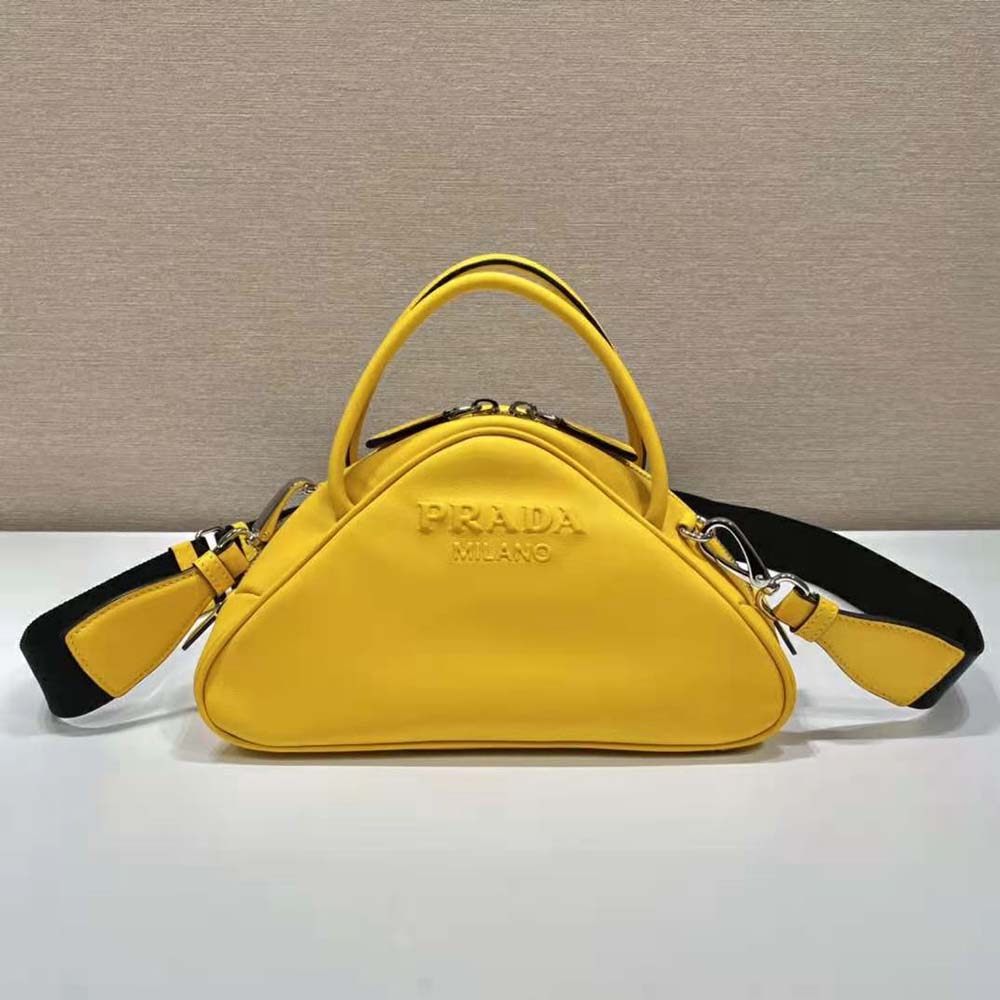 Close-up of silver Prada triangle logo on yellow leather bag