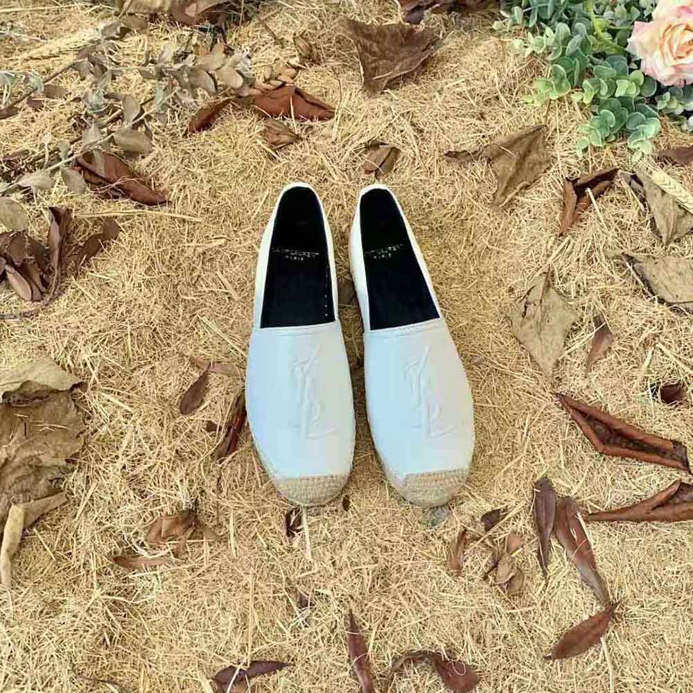 Close-up of gold YSL monogram on white lambskin espadrilles