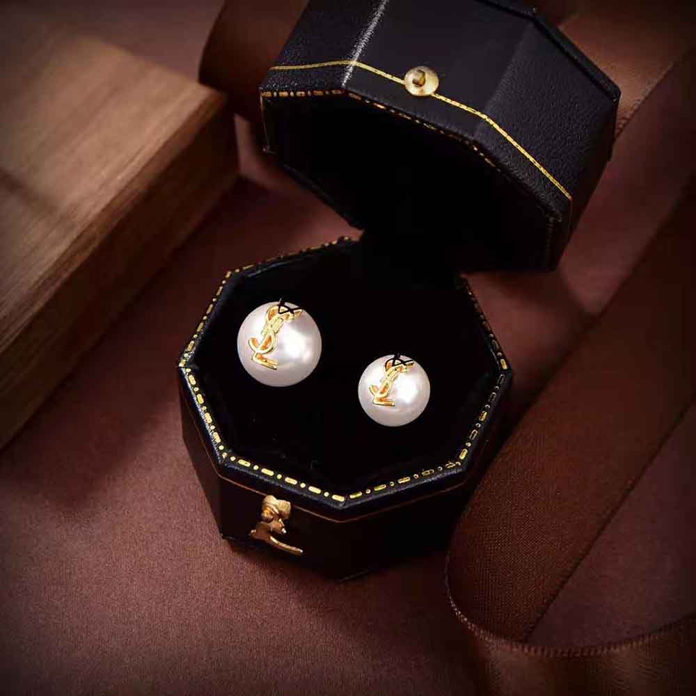Close-up detail of YSL logo on pearl earrings in metal