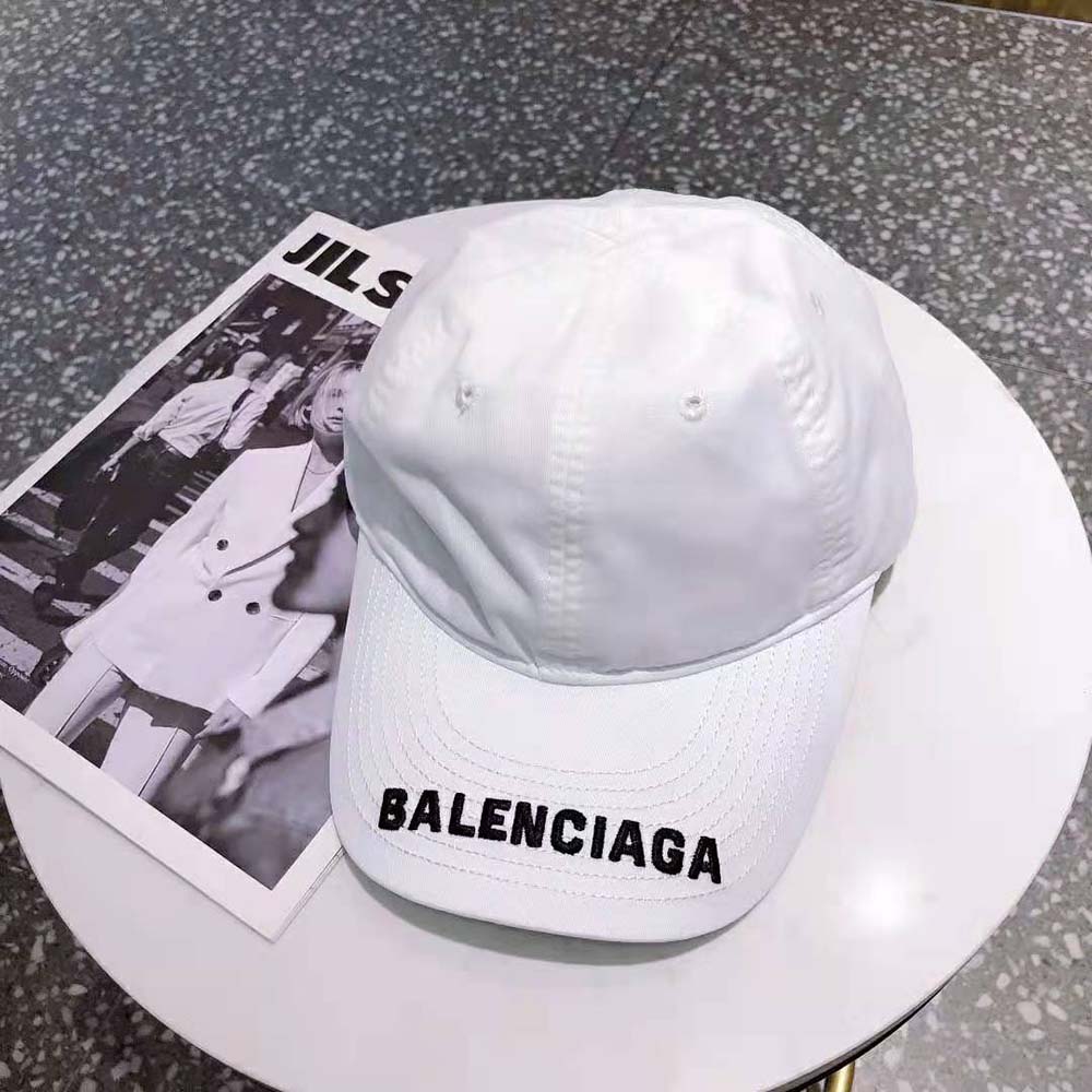 Close-up of embroidered black Balenciaga logo on white visor cap