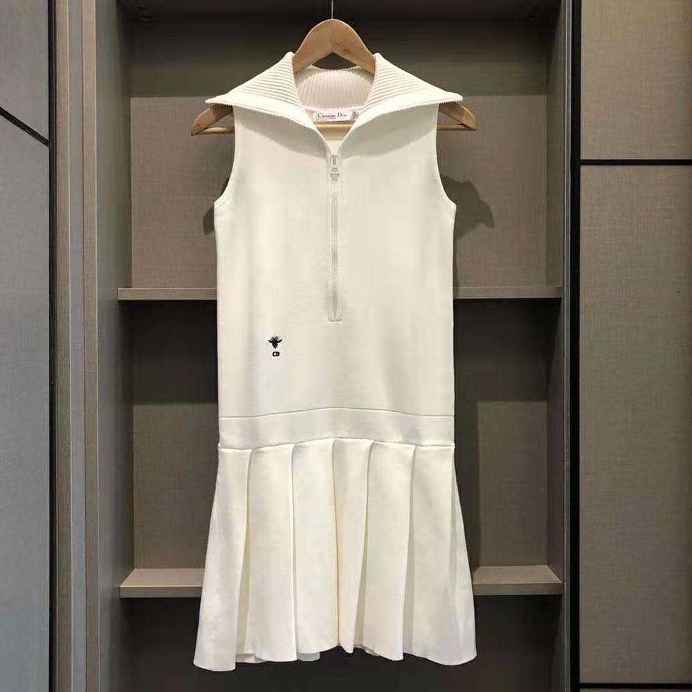 Close-up on fabric texture and Dior hardware detail on white dress