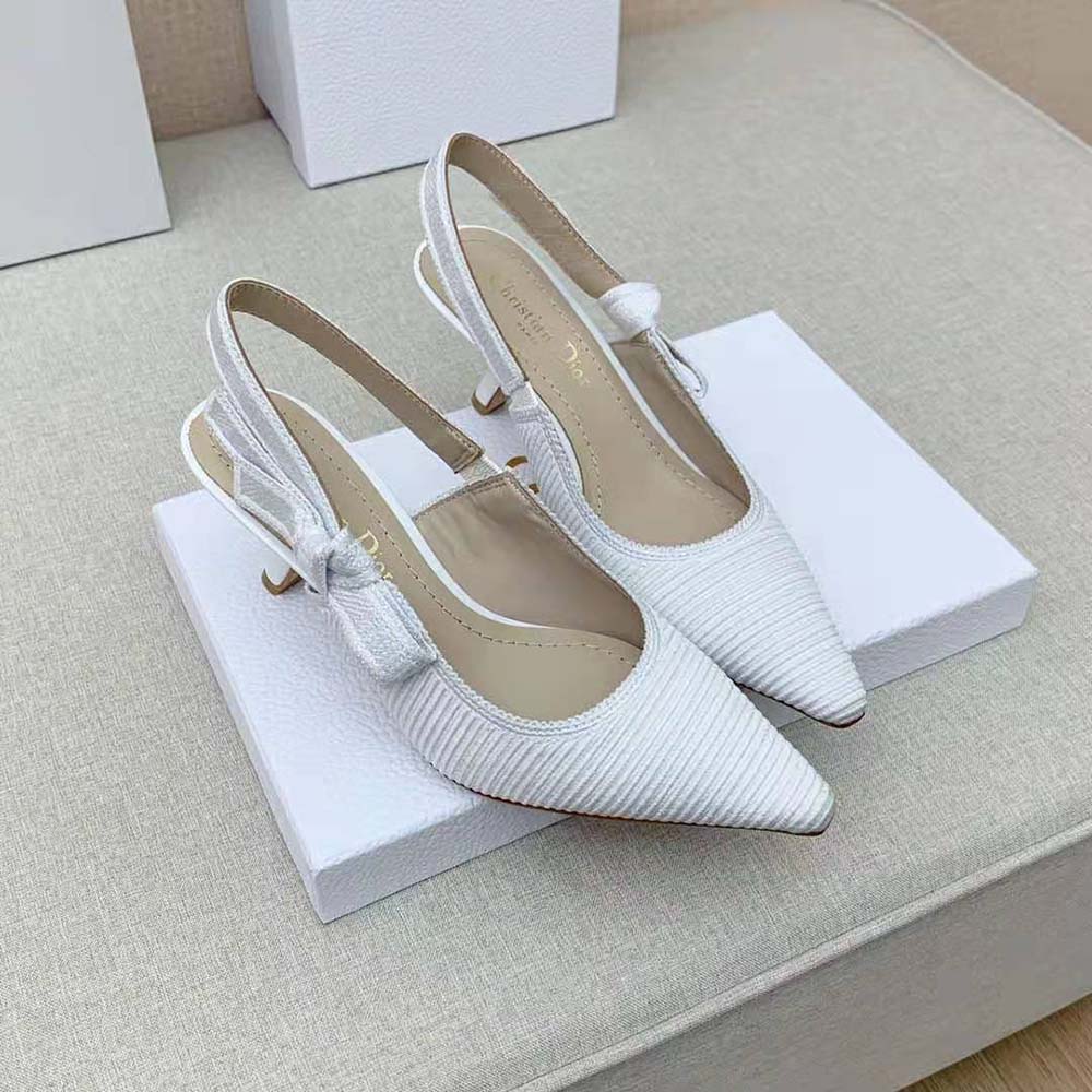 Close-up detail of white cotton embroidery and gold hardware on Dior slingback