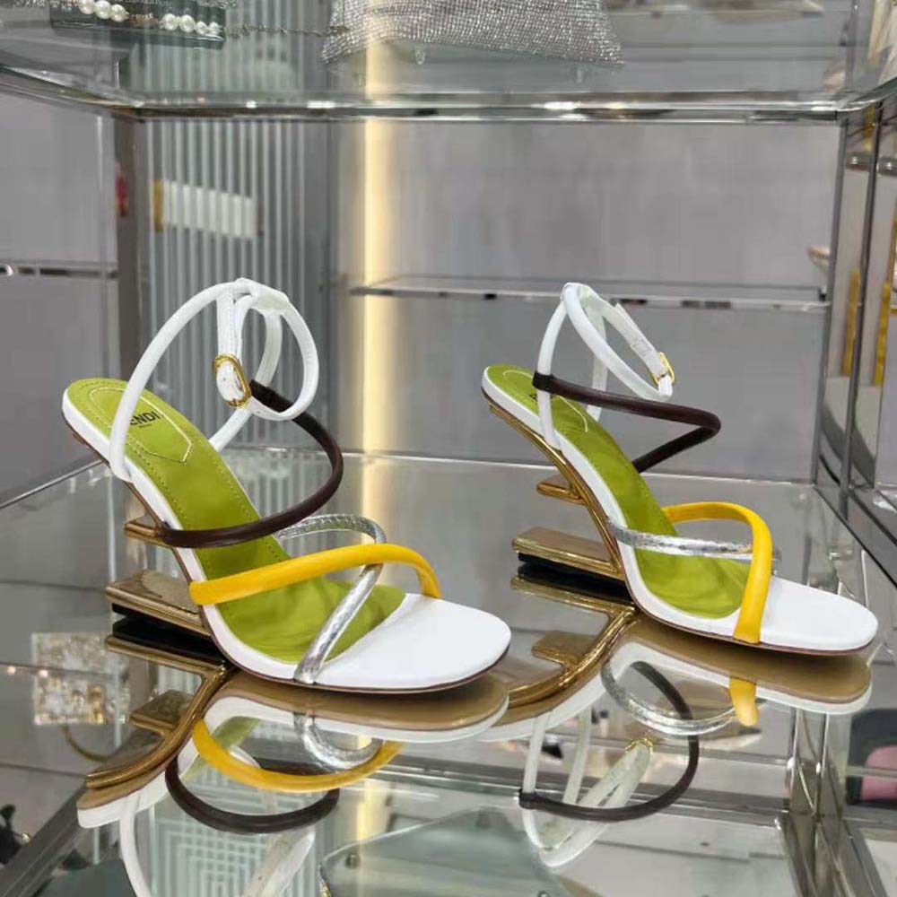 Close-up on gold-tone Fendi hardware on white leather sandal strap