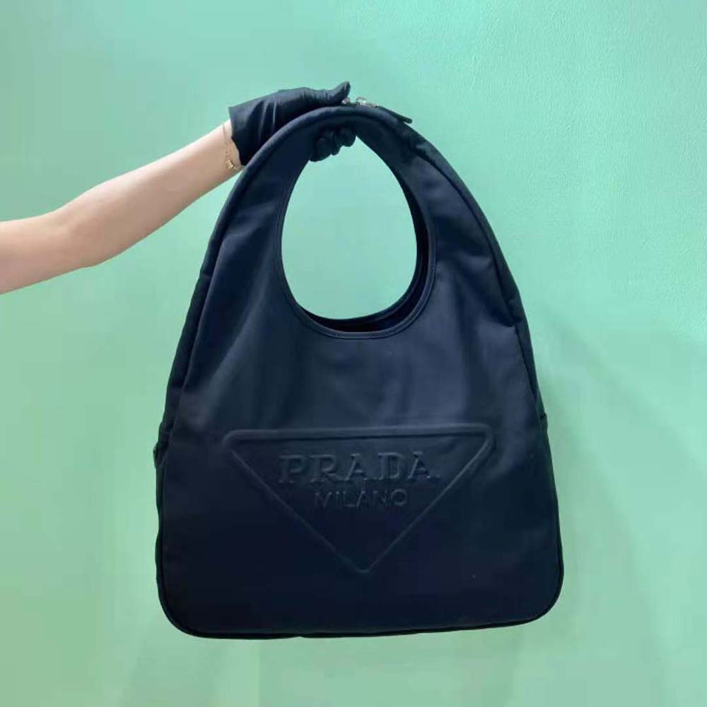 Close-up of embossed Prada logo and silver-tone hardware on black canvas bag