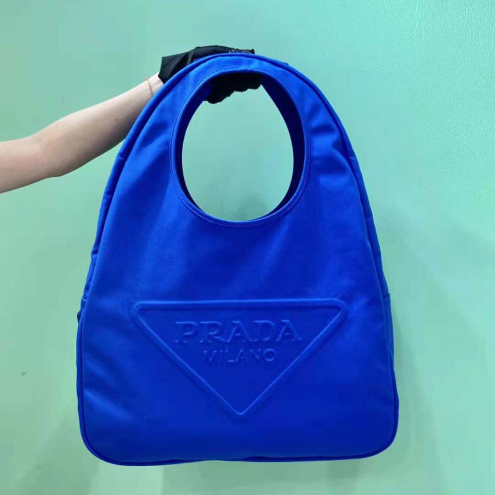 Close-up of silver-tone hardware and embossed logo on blue Prada hobo bag