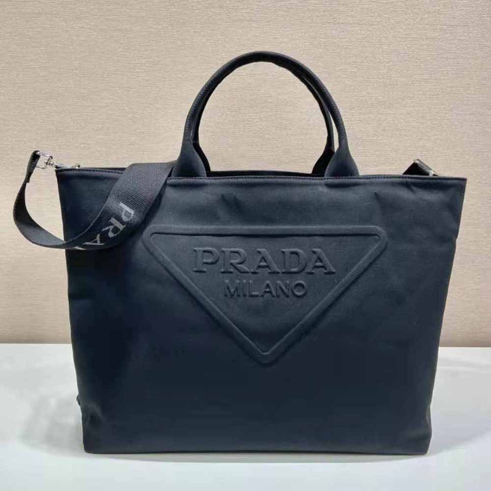 Close-up of silver-tone Prada logo hardware on black canvas tote bag