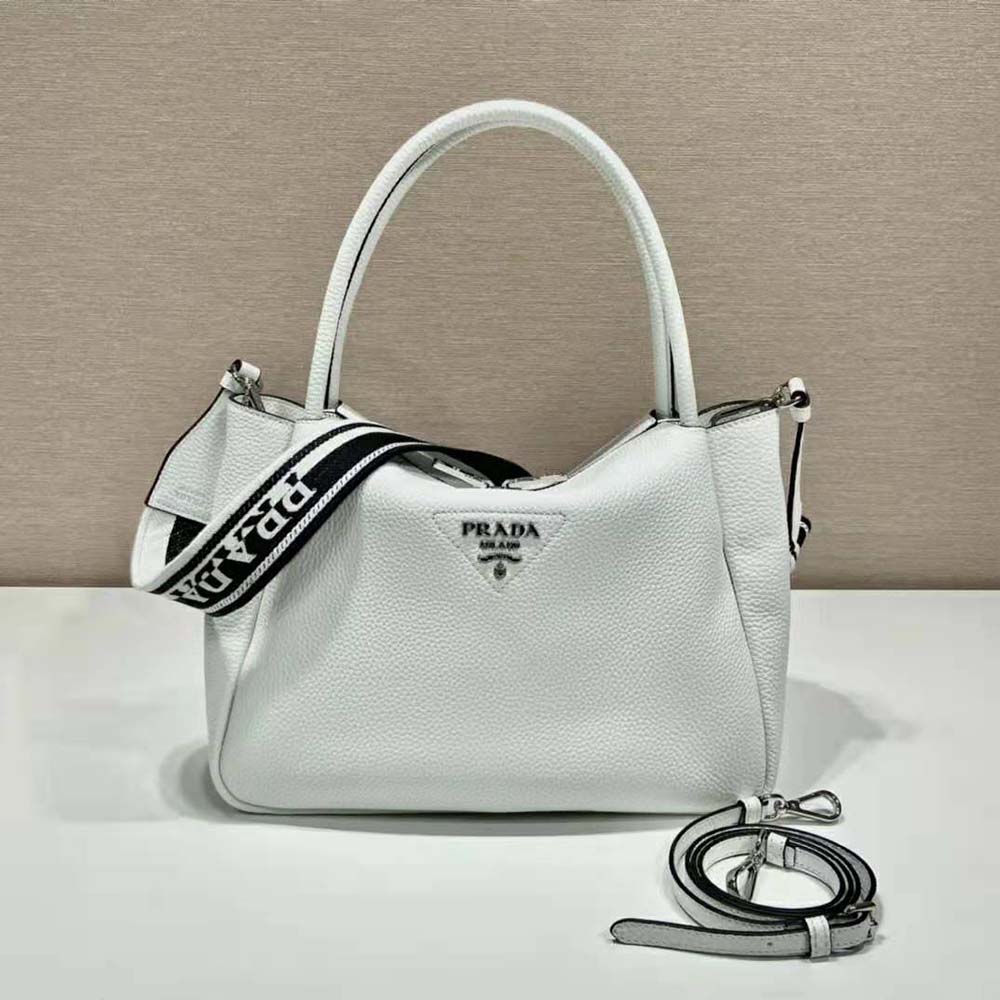 Close-up detail of Prada metal lettering logo on white leather handbag