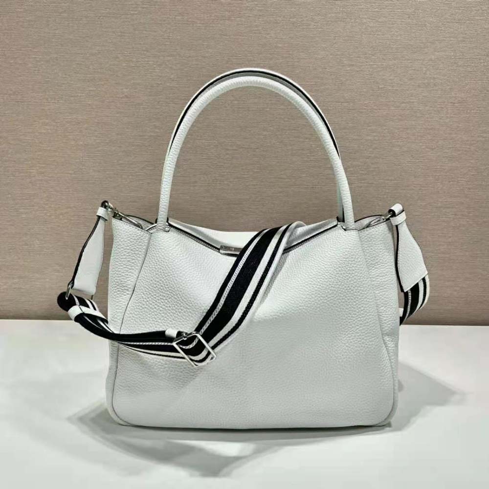 Side angle showing large silhouette and silver hardware of Prada white handbag