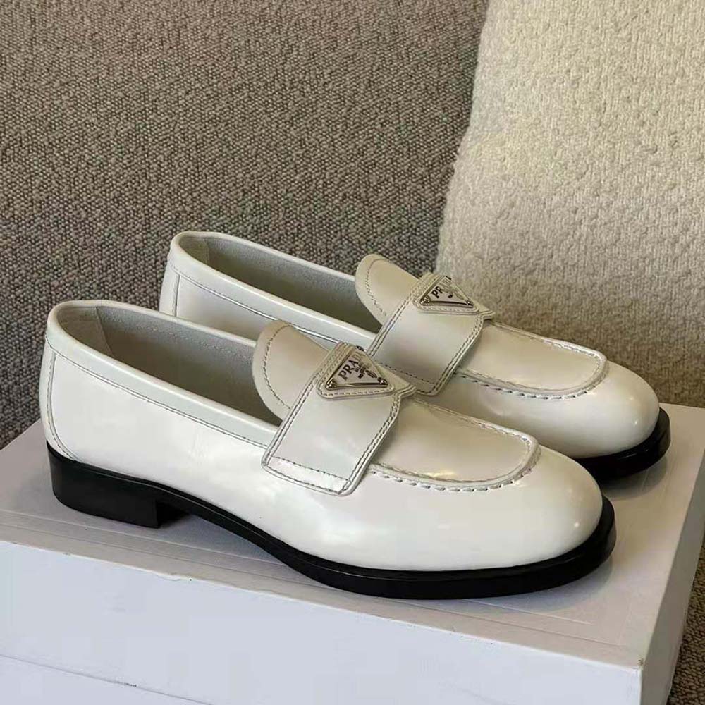 Top view showing signature Prada metal logo on white loafers