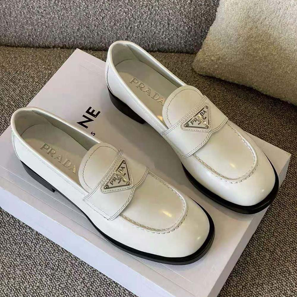 Close-up detail of glossy white patent leather on Prada loafers