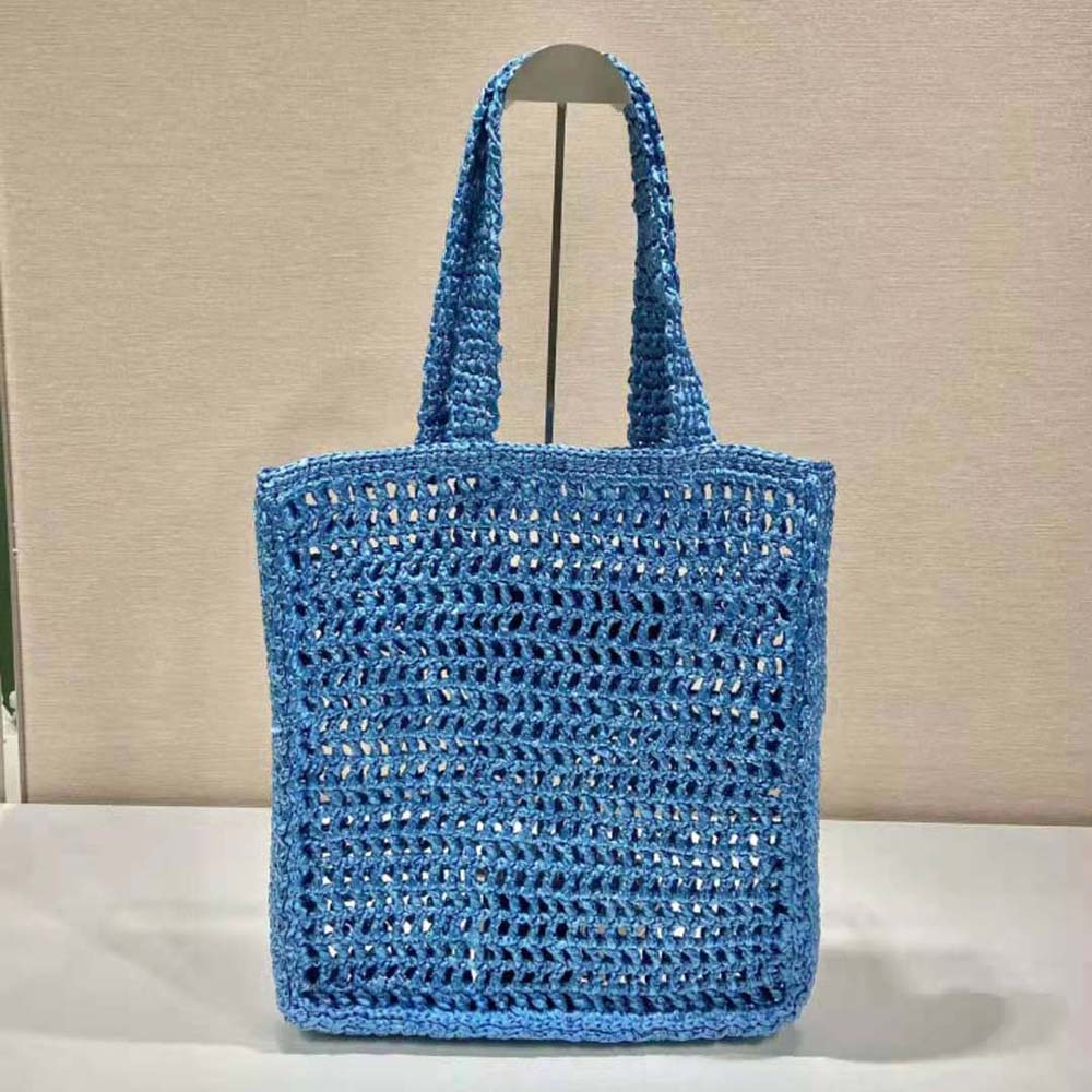 Side angle showing soft-blue leather handles on Prada raffia bag