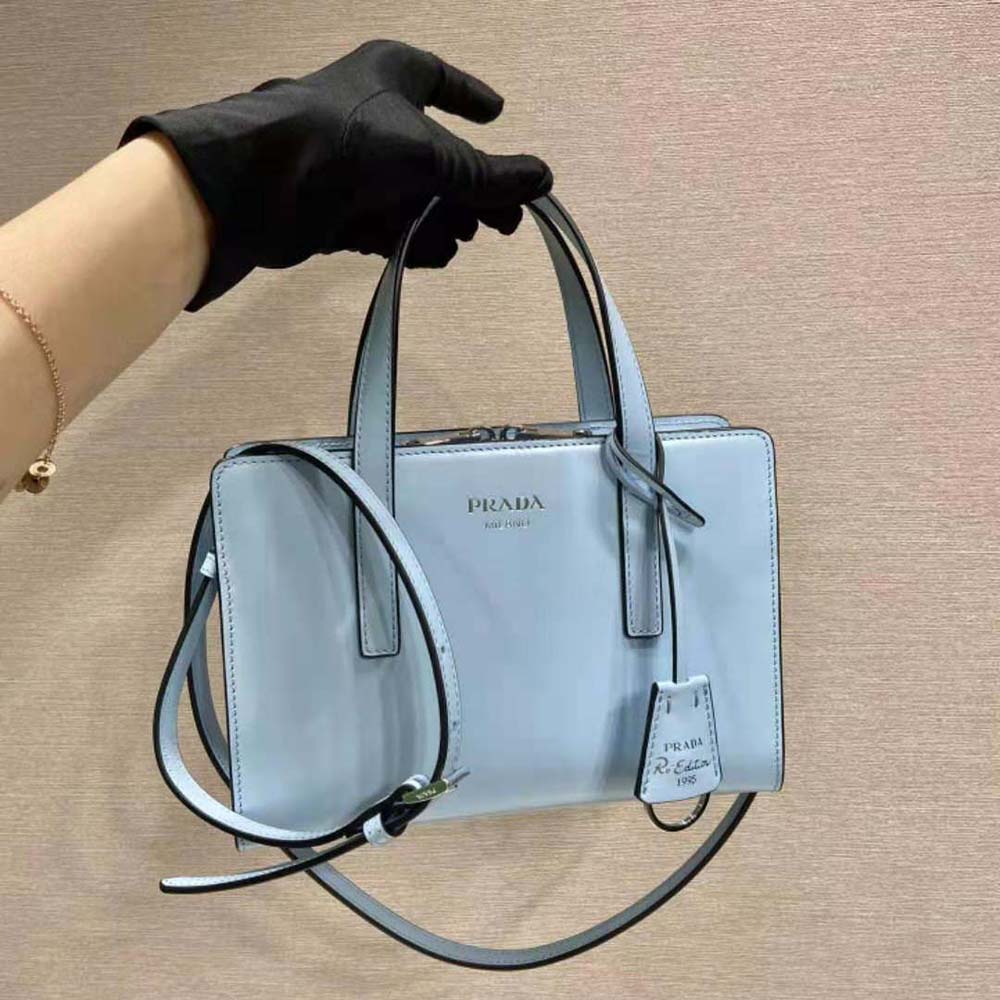 Close-up of silver Prada logo on blue brushed leather mini handbag