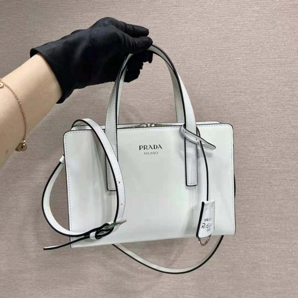 Close-up of Prada triangular logo on white brushed leather mini handbag