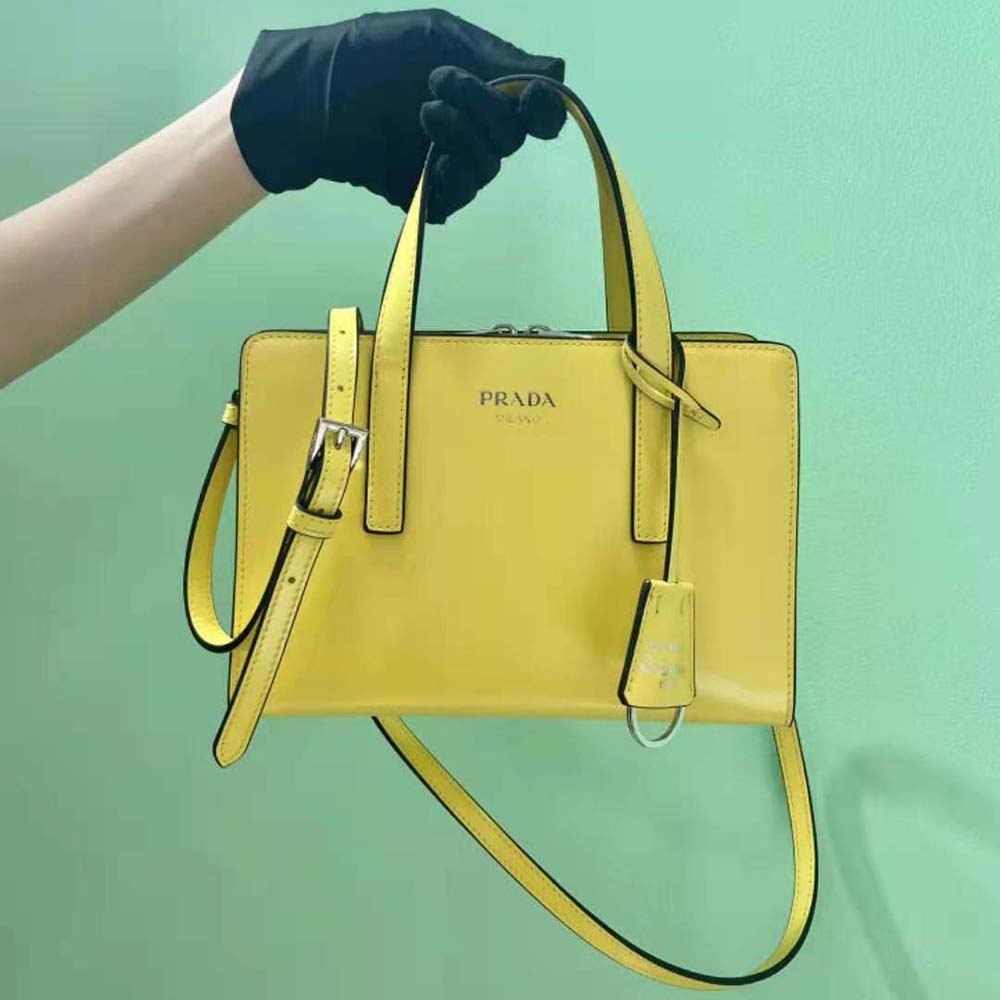 Close-up of yellow brushed leather and silver Prada logo plaque handbag