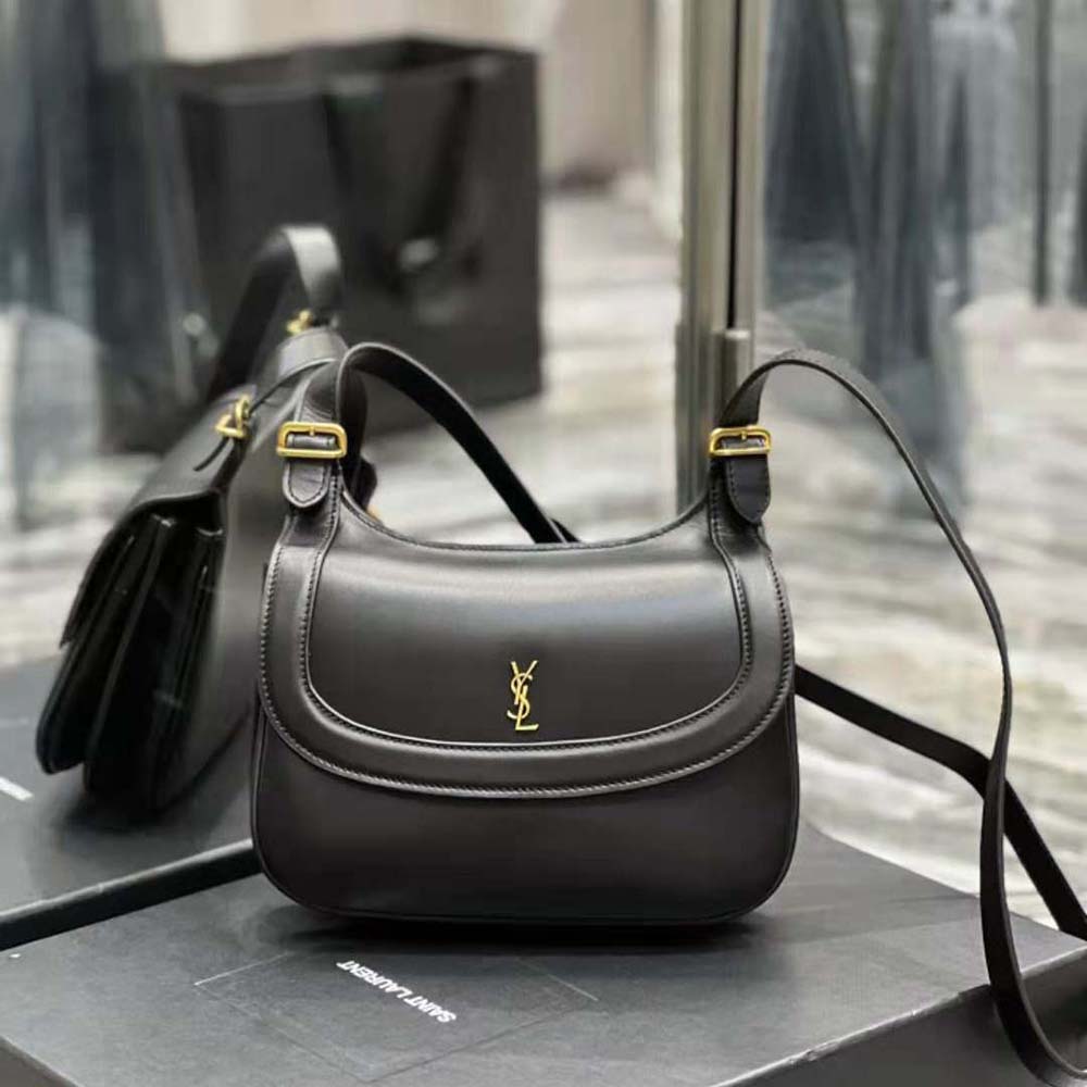 Close-up detail of gold YSL logo hardware on black smooth leather bag
