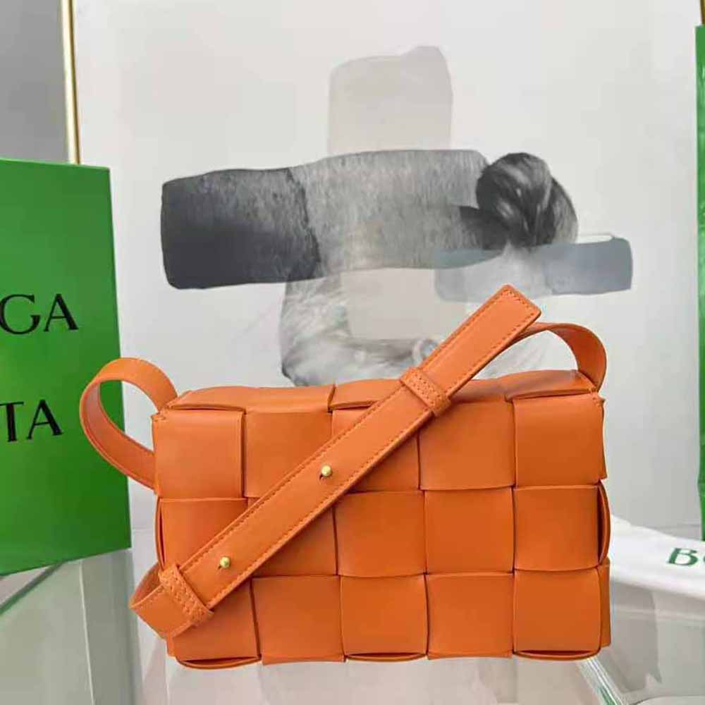 Side angle showing matte gold hardware and orange leather bag strap