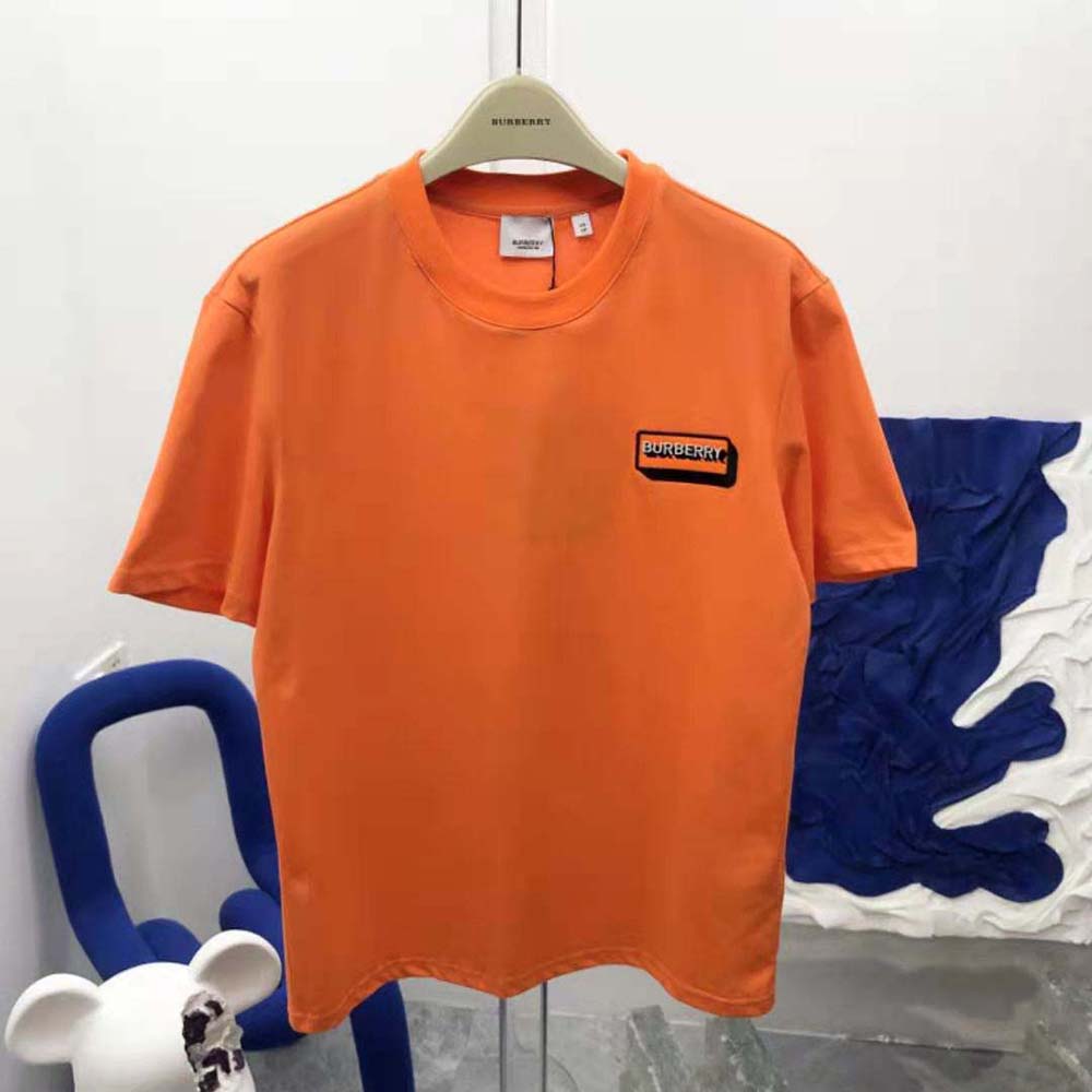 Close-up detail of Burberry logo appliqué on orange oversized T-shirt