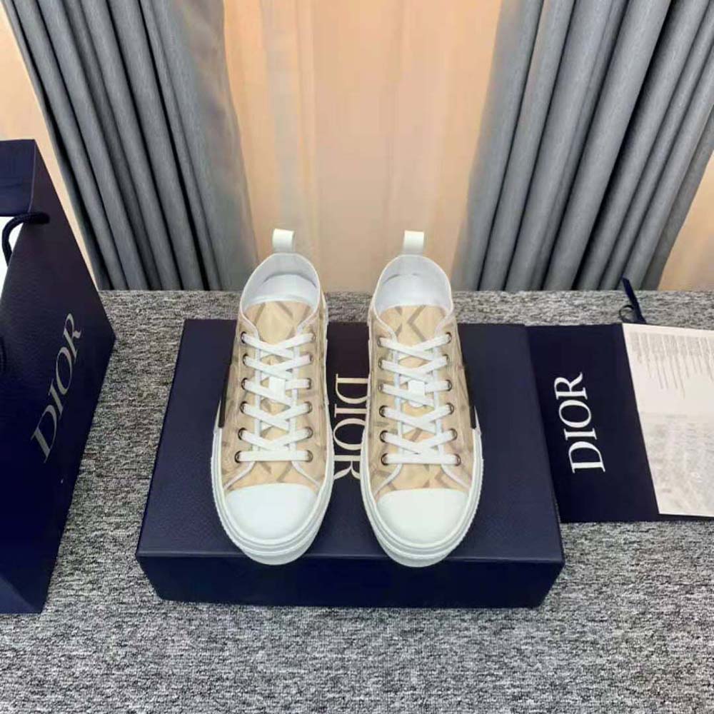 Close-up of beige diamond canvas and CD logo hardware on sneaker