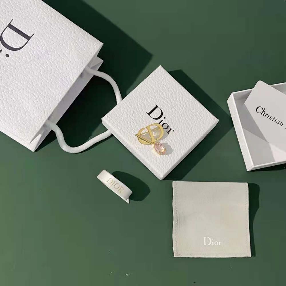 Close-up detail of amber crystal and gold finish on Dior Women Petit CD Brooch