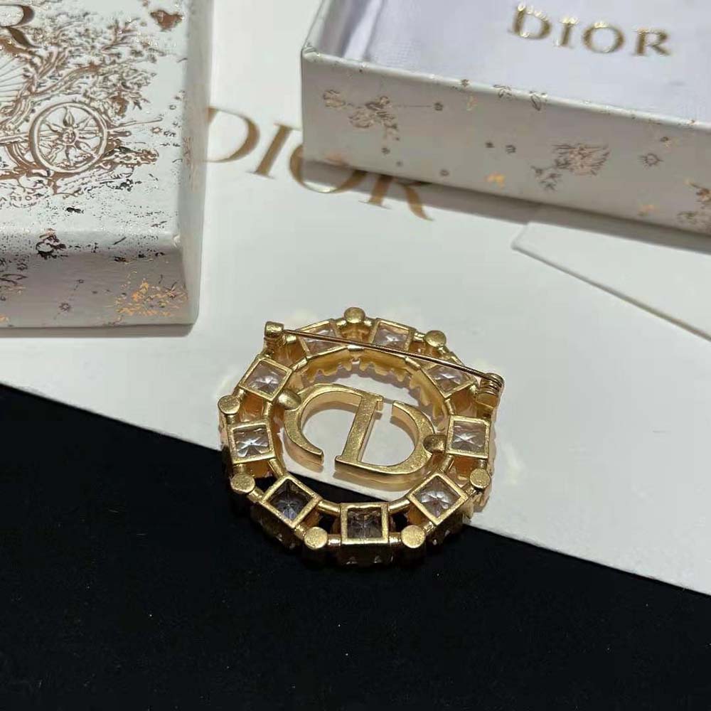 Dior Women Petit CD Brooch pinned on gold fabric background