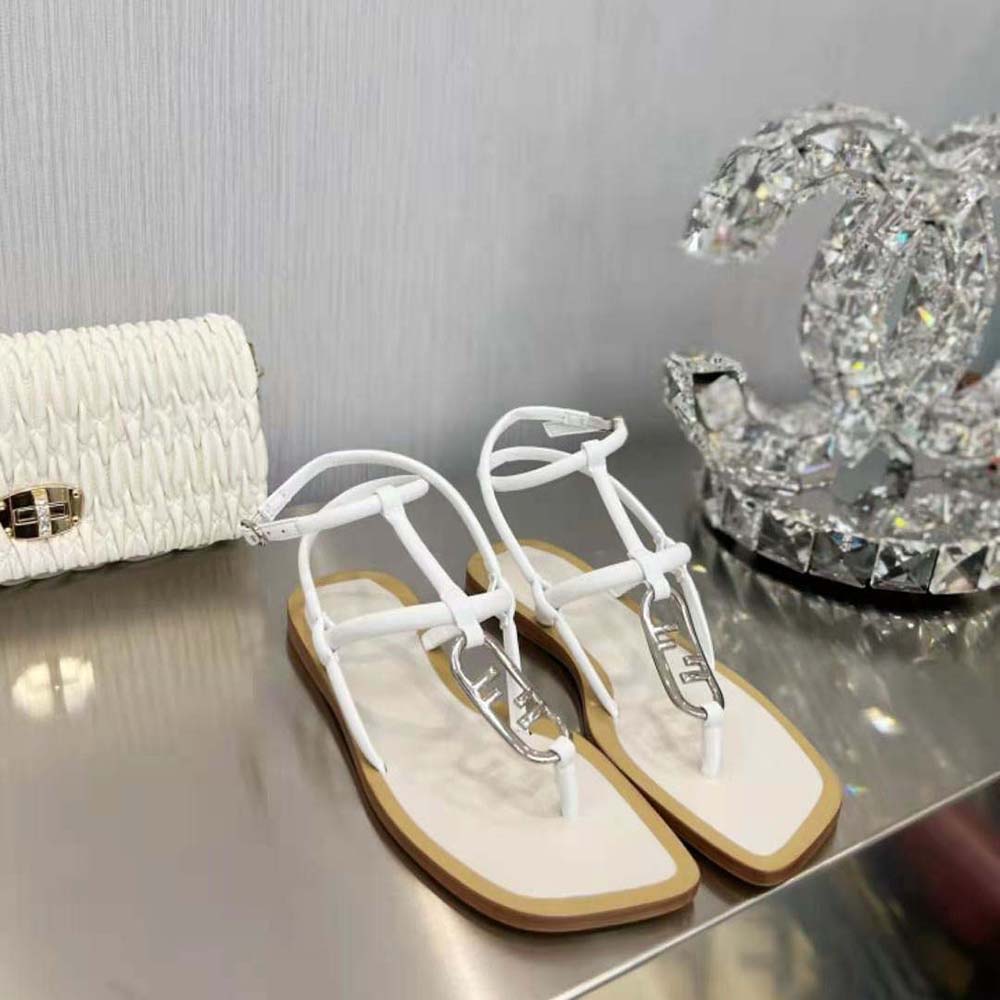 Close-up of signature gold O Lock hardware on white leather sandal