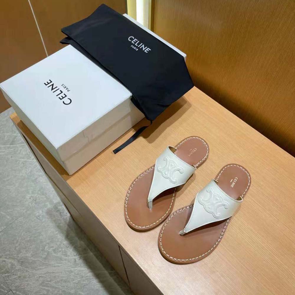 Close-up detail of gold Triomphe logo on white calfskin sandal strap