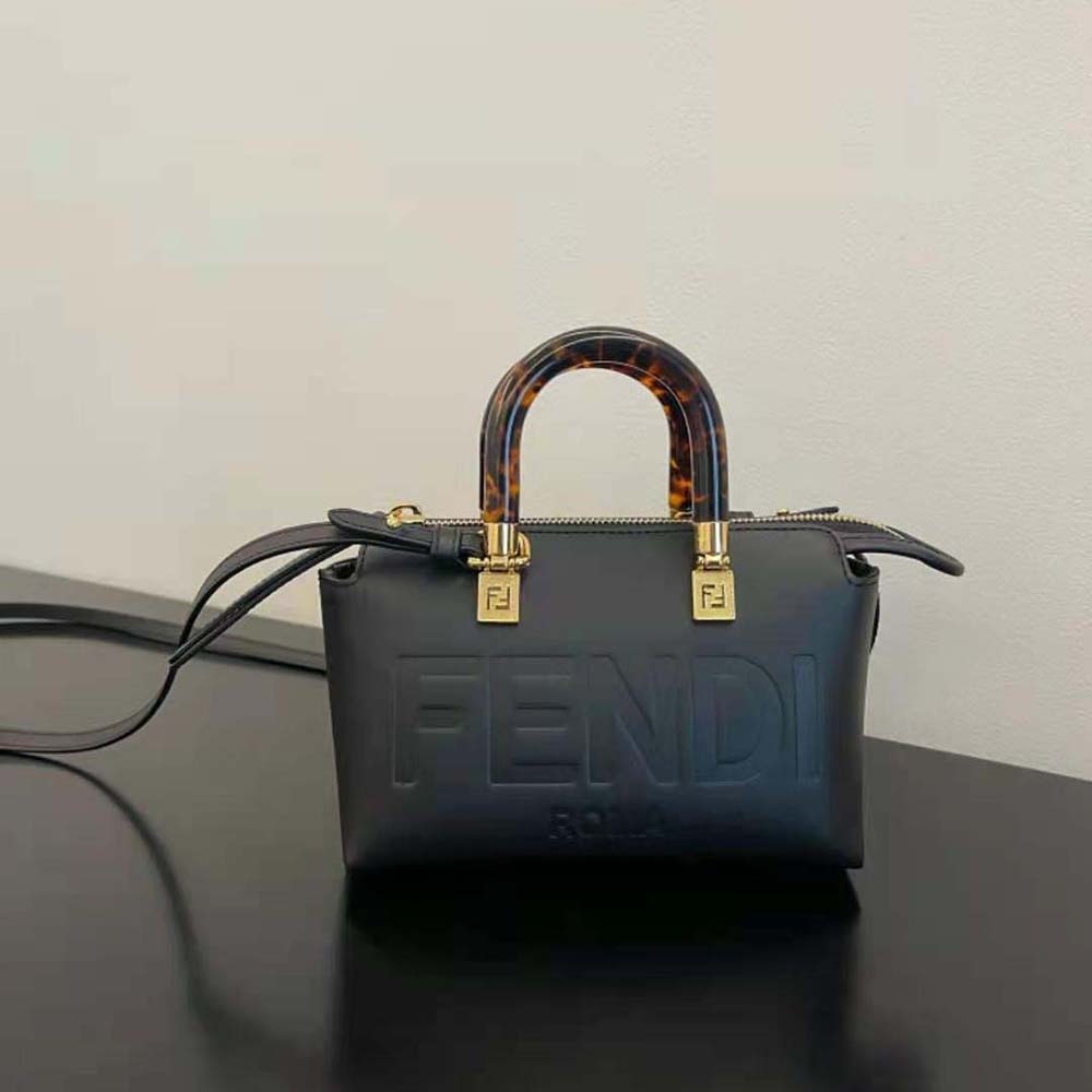 Close-up of gold-tone Fendi logo hardware on black leather bag