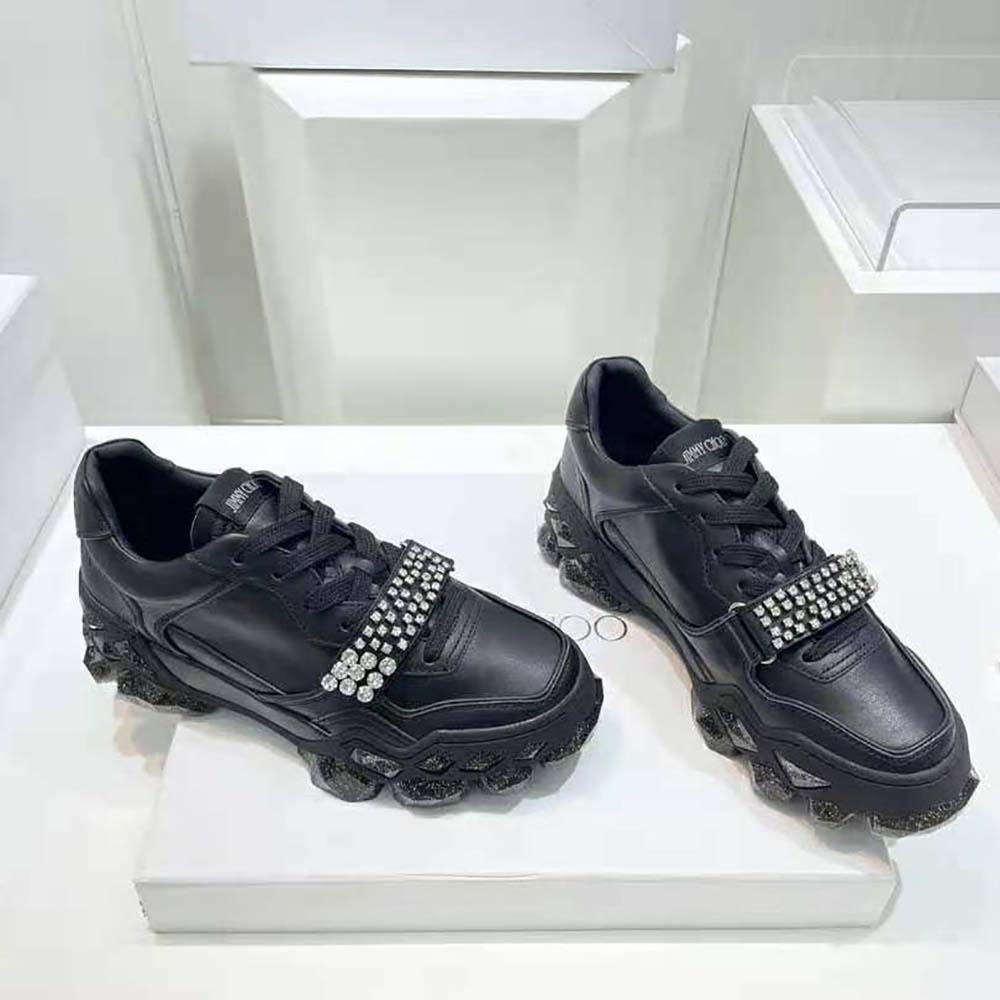 Top-down angle showcasing sleek black leather and crystal strap on Jimmy Choo trainers