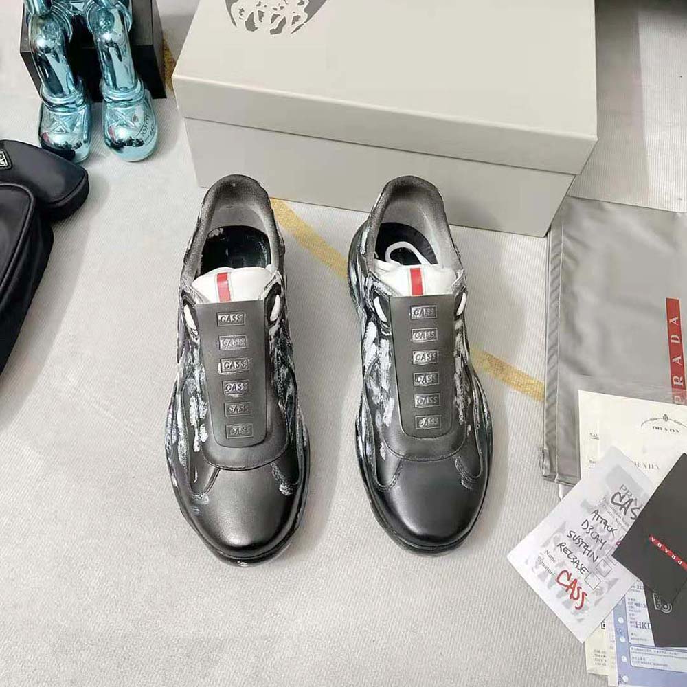 Close-up of metallic Prada Americas Cup emblem on black sneaker