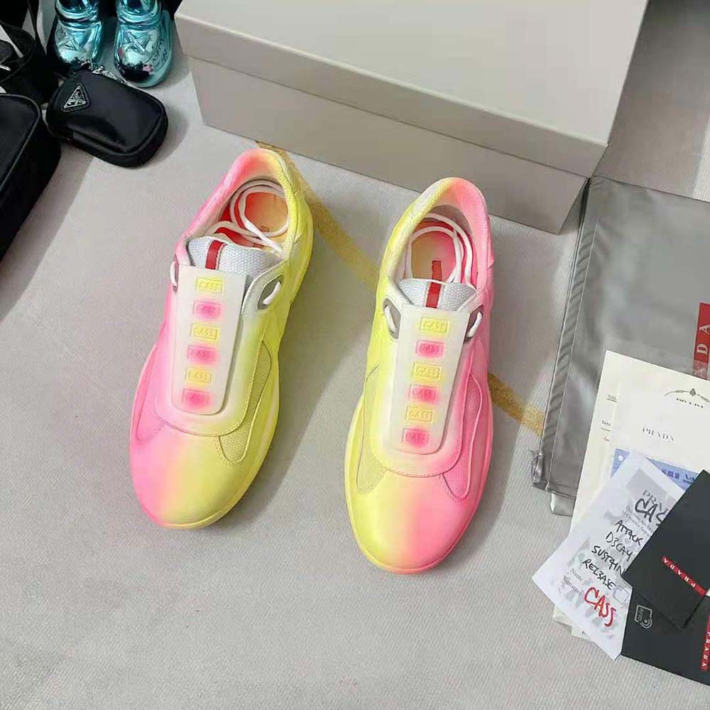 Close-up detail of yellow mesh and Prada branding on sneakers