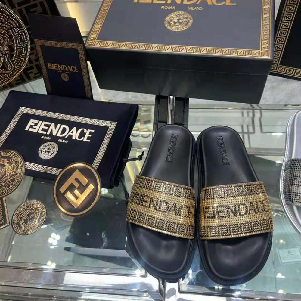 Close-up detail of Versace Fendace logo hardware on black sliders