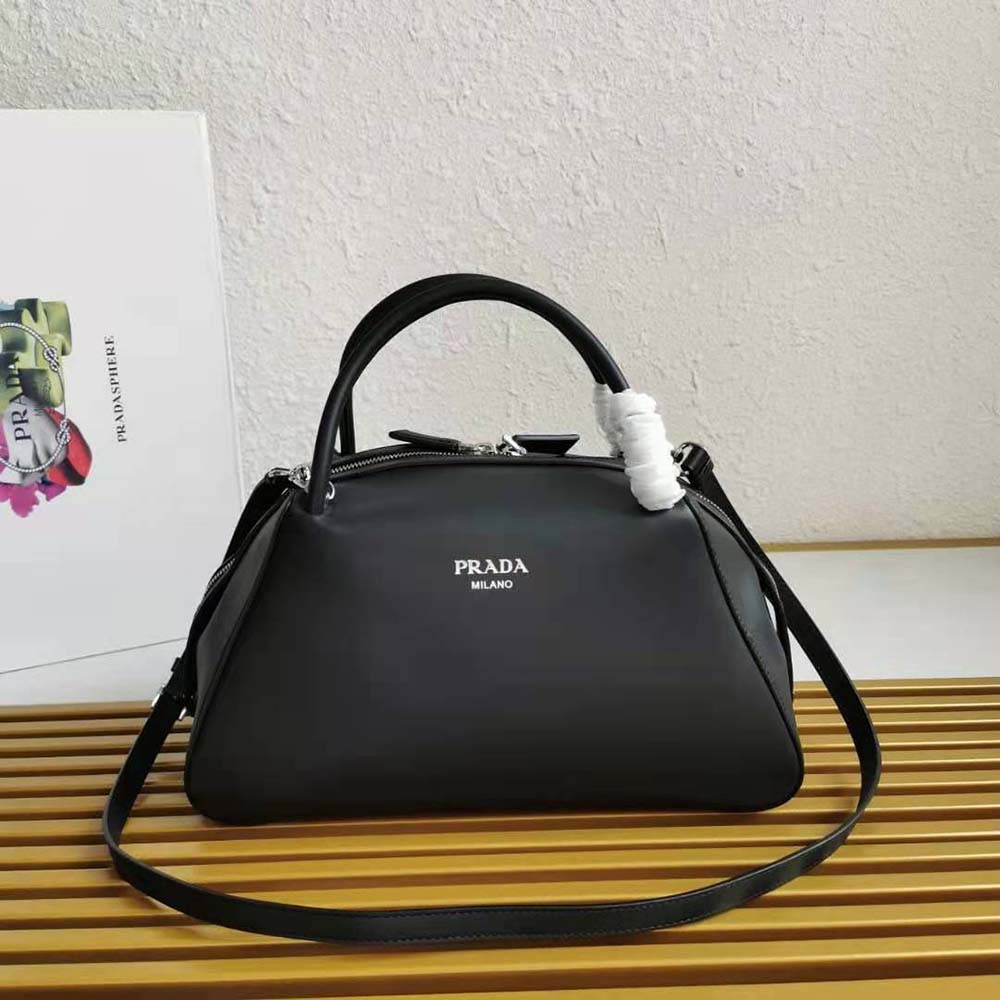 Close-up of silver Prada logo on black leather handbag