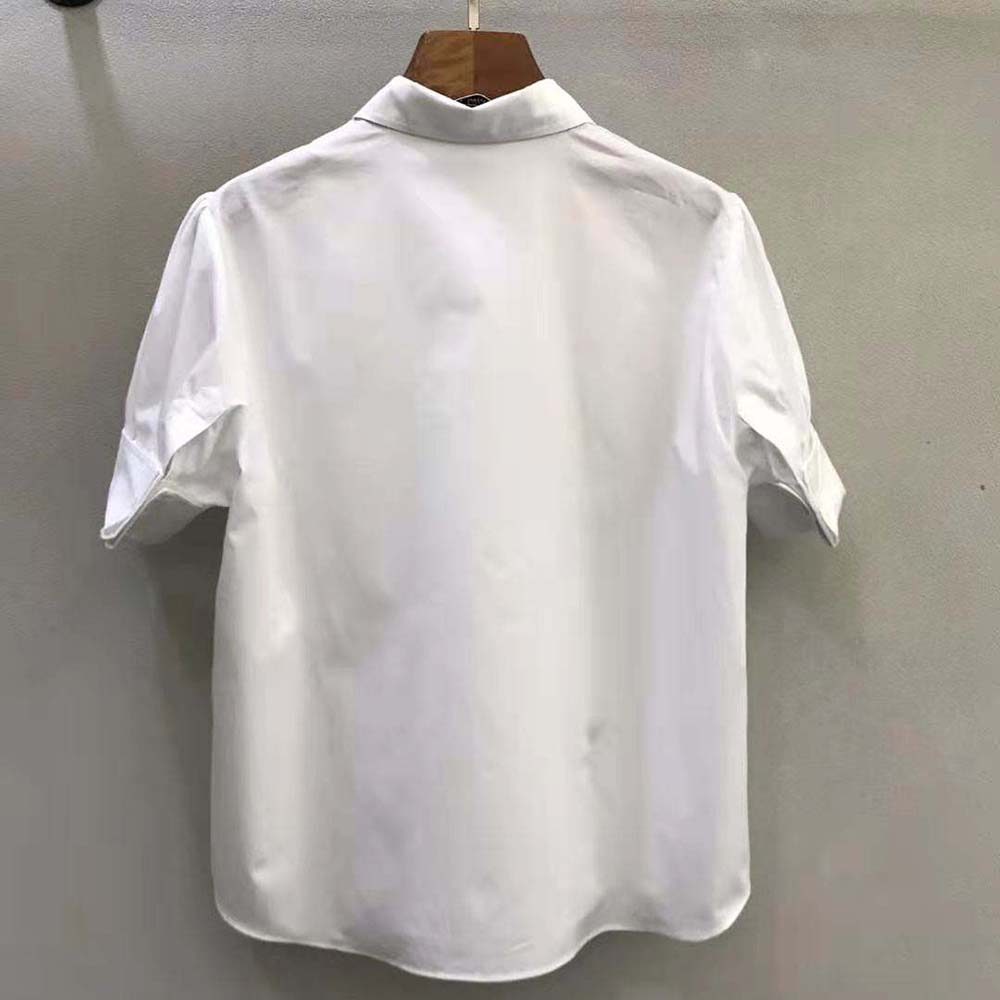 Detail of button closure and Dior stitch on white blouse
