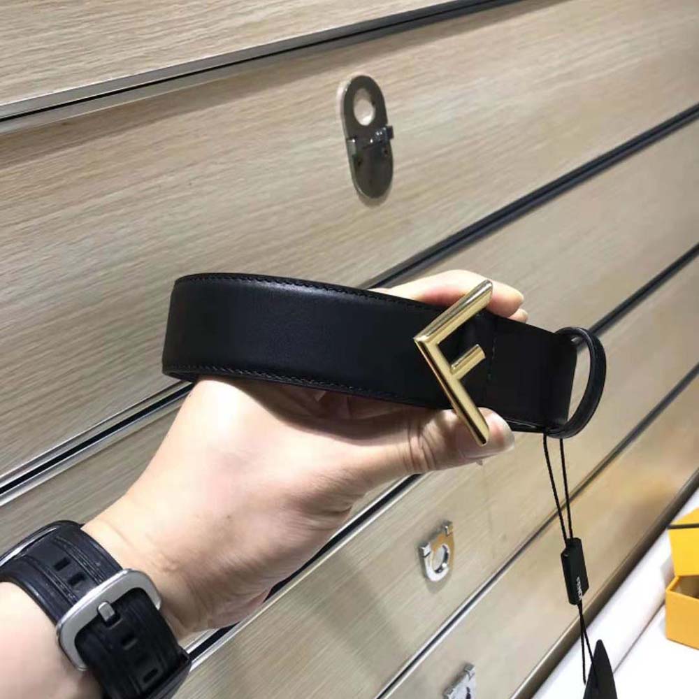 Close-up on signature gold Fendi buckle detail on black leather belt