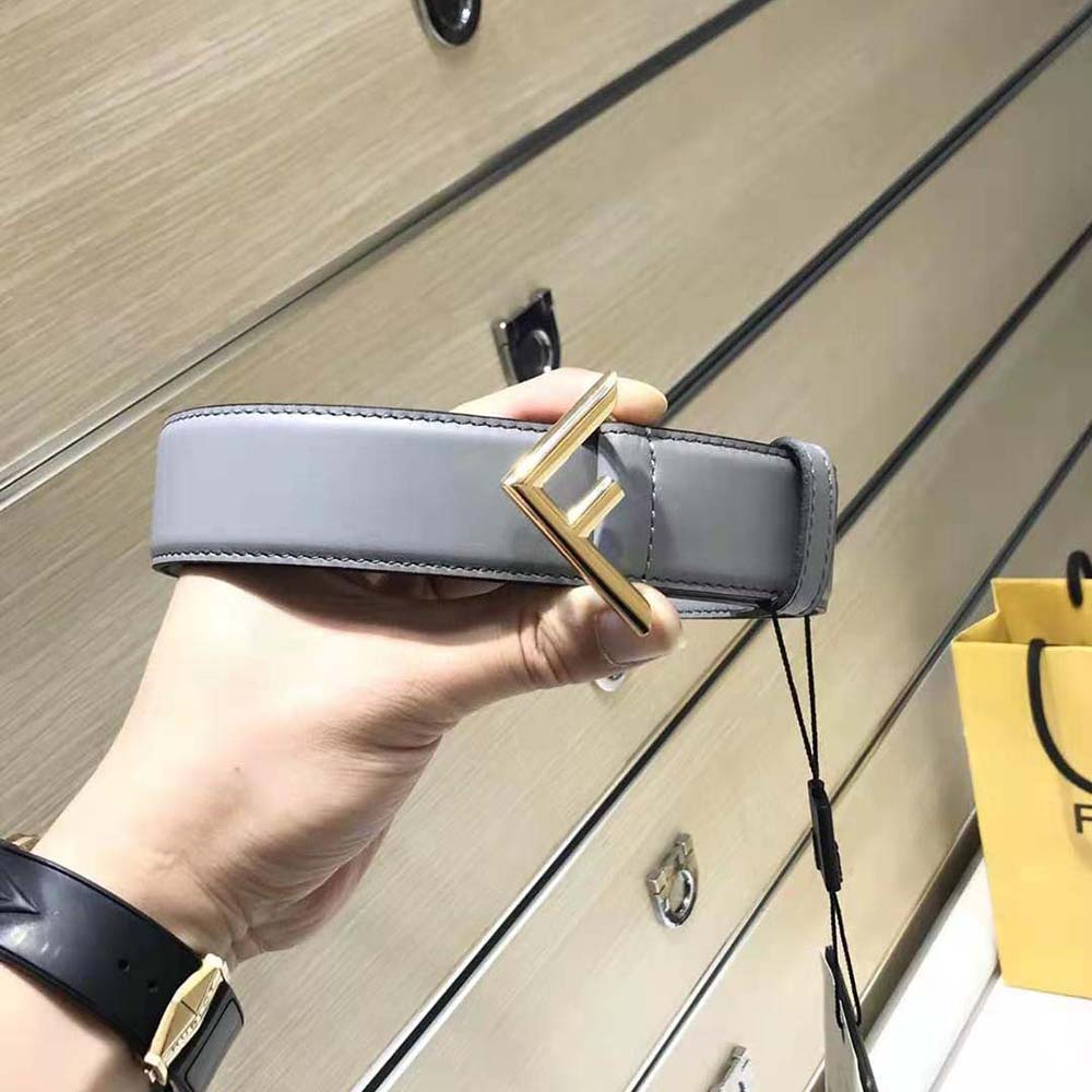 Close-up of Fendi logo engraved hardware on gray leather belt