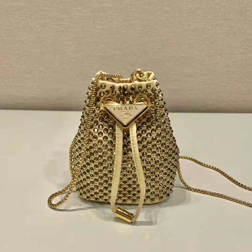 Close-up of golden satin fabric and crystal embellishments on Prada mini-pouch