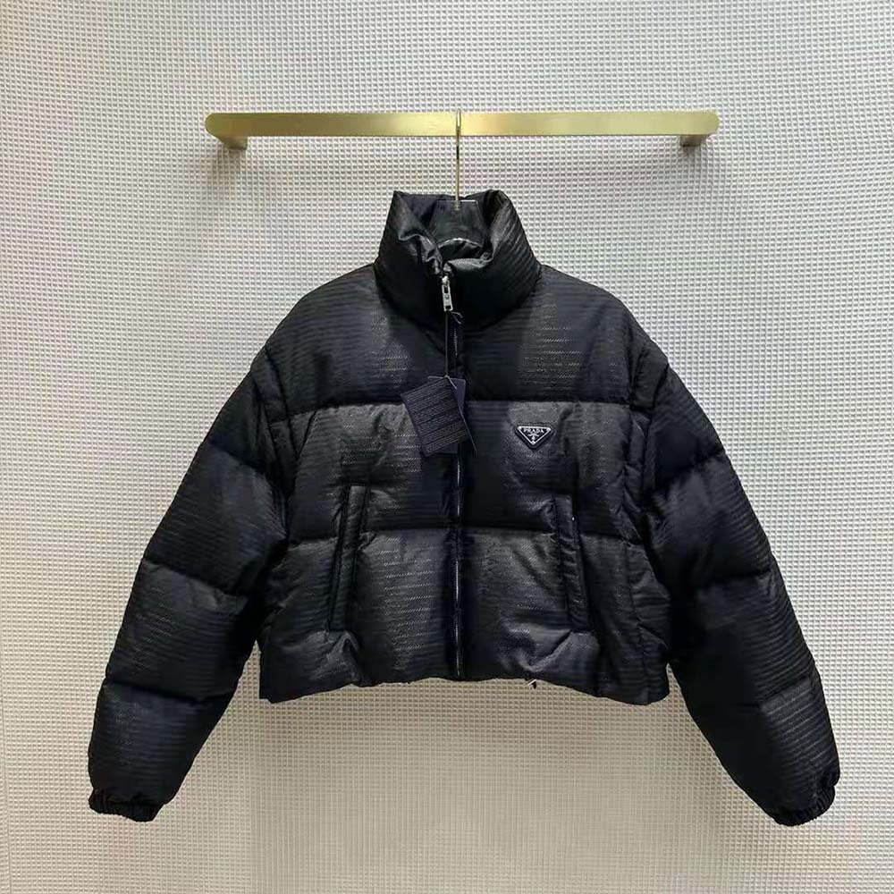 Close-up of signature Prada logo hardware on black Re-Nylon jacket