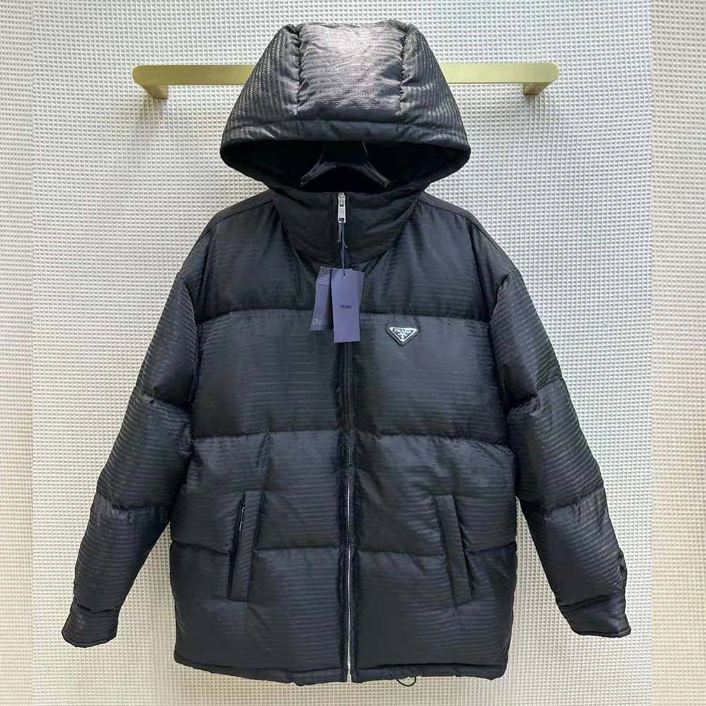 Close-up of Prada triangle logo plaque on black Re-Nylon jacket