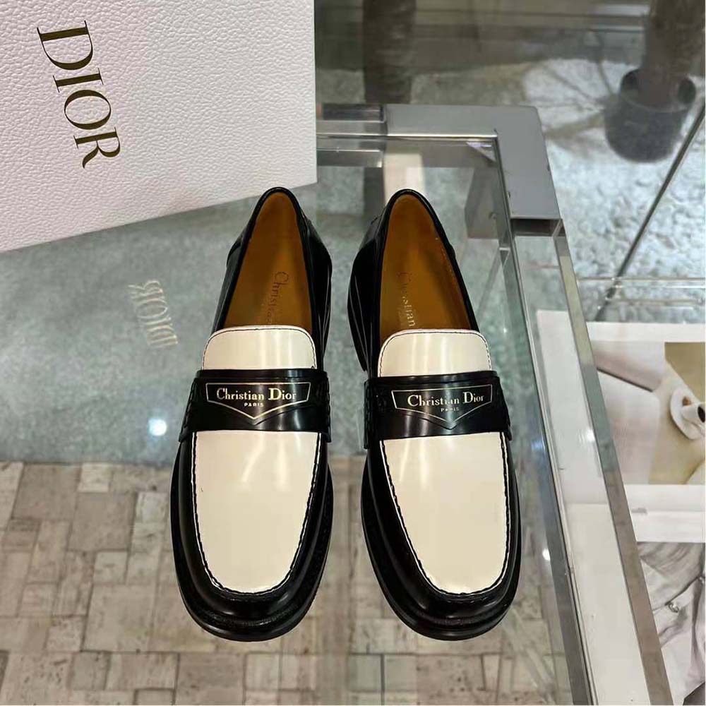 Close-up on metal Dior hardware on black and white loafer