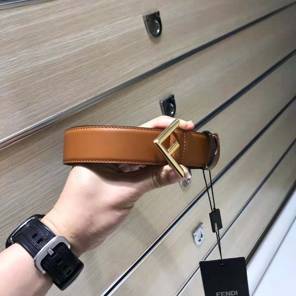 Close-up detail of Fendi gold buckle on brown leather belt