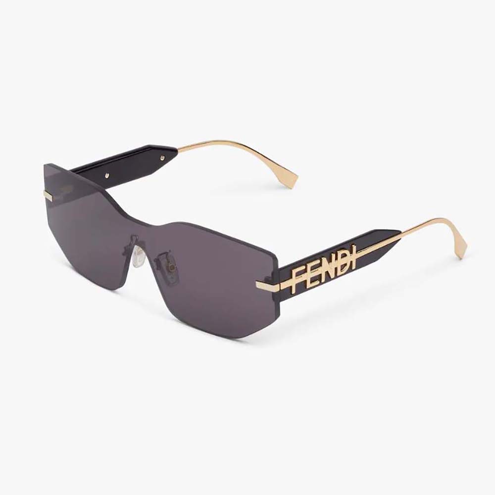 Close-up on gold Fendigraphy logo hardware on black shield sunglasses temple