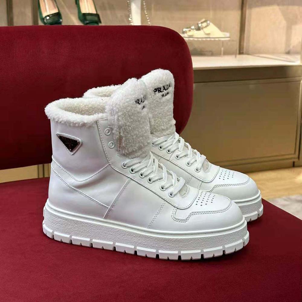 Close-up of Prada logo hardware on white leather sneakers