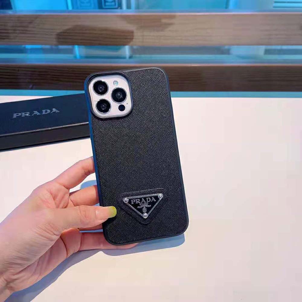 Close-up detail of Prada gold-tone logo on black leather iPhone cover
