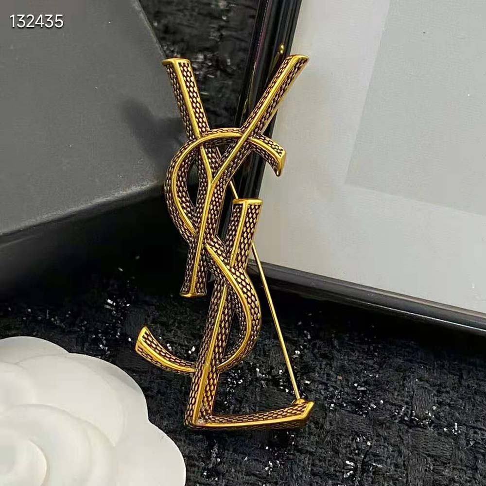 Top-down view of gold Saint Laurent YSL Women Opyum Ysl Snake Brooch highlighting intertwined logo