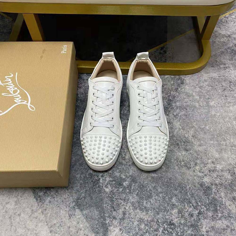Close-up of white leather and signature spikes on Christian Louboutin sneakers