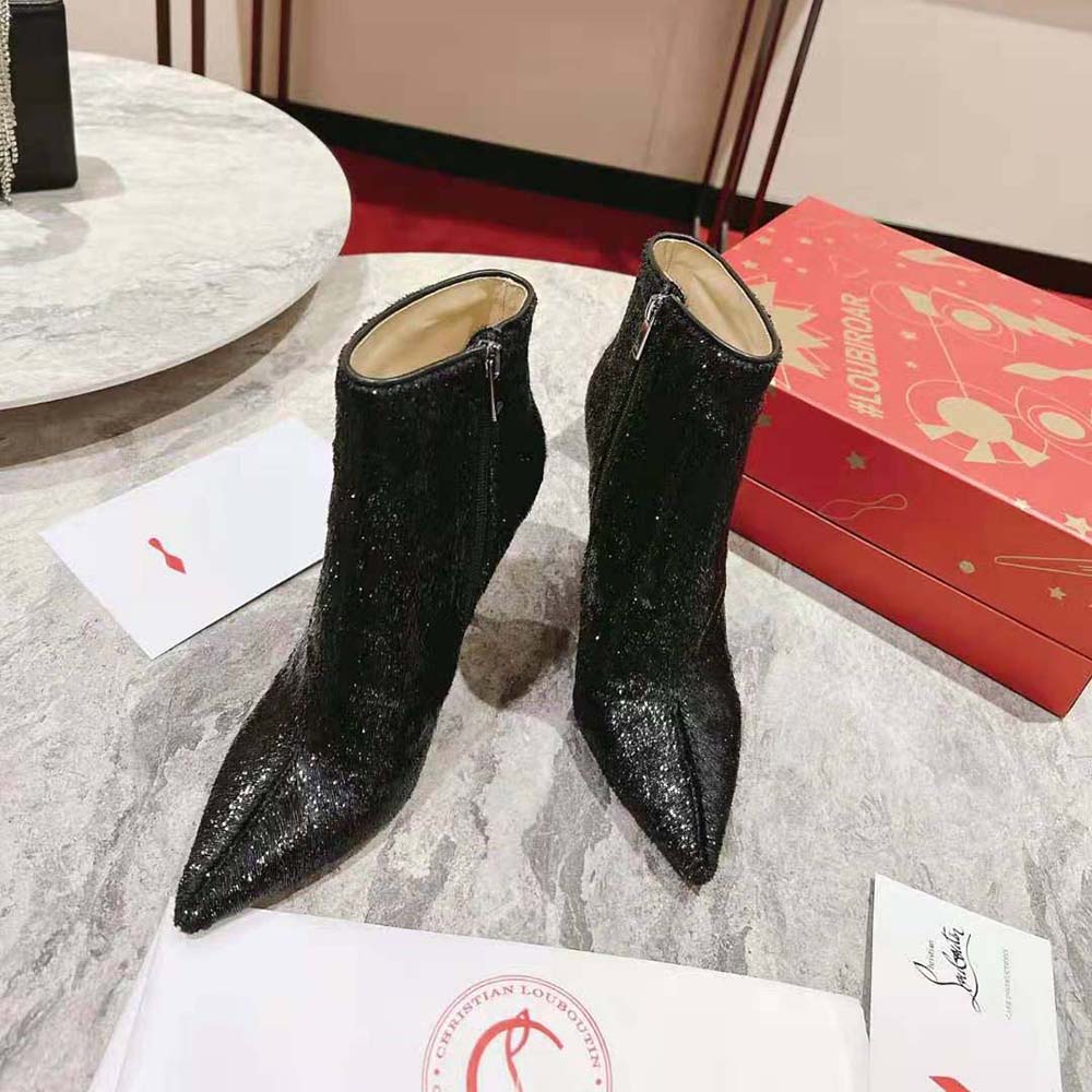 Close-up on black patent leather and red sole detail of Christian Louboutin boot