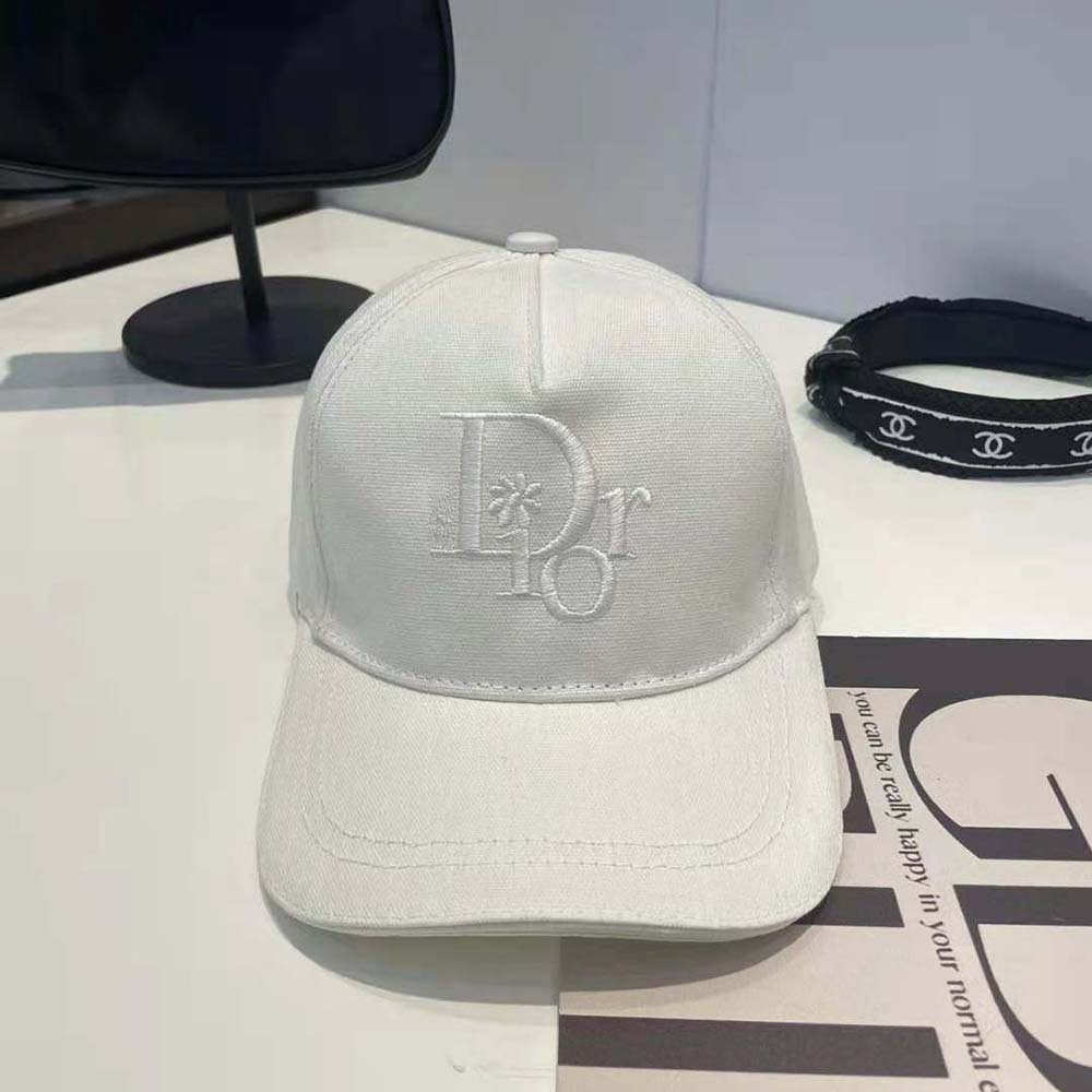 Close-up of embroidered Dior logo on white cotton cap